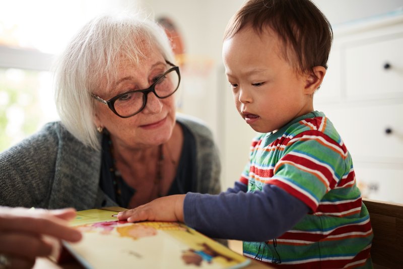 Foto: Eine Heilpädagogin betrachtet mit einem kleinen Jungen ein Bilderbuch