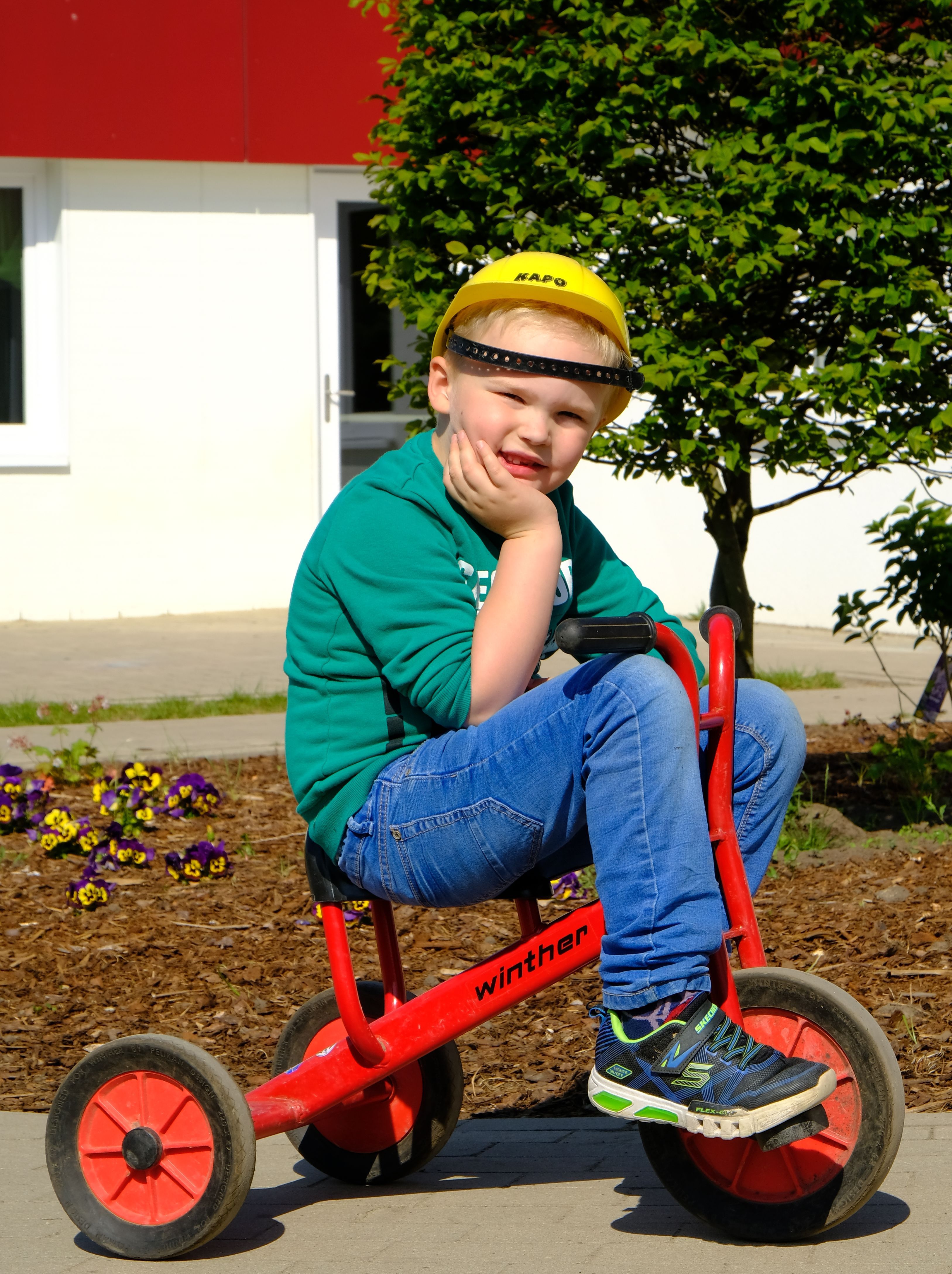 Foto: Ein Junge mit Bauarbeiterhelm sitzt auf einem Dreirad