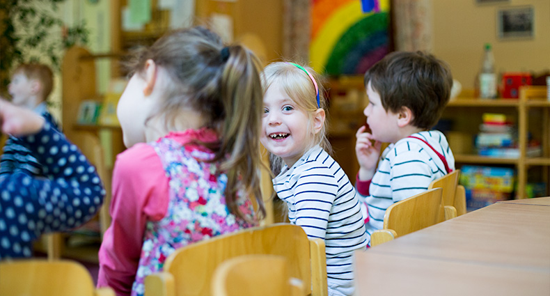 Foto: Ein Mädchen im Kindergarten lacht in die Kamera